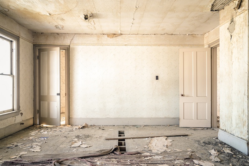 an empty room with damaged floor and ceiling